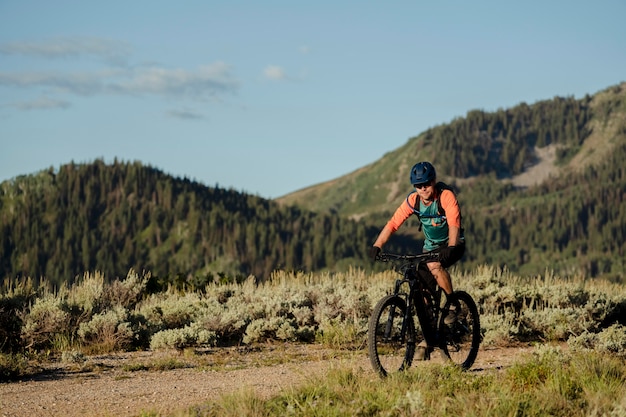 Foto gratuita adulto joven con bicicleta eléctrica en el campo