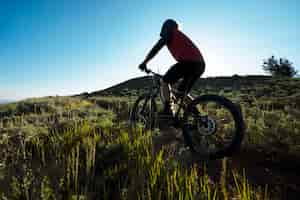 Foto gratuita adulto joven con bicicleta eléctrica en el campo