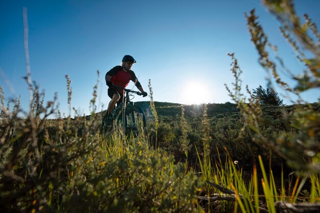 Adulto joven con bicicleta eléctrica en el campo