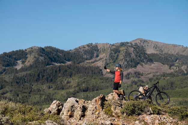 Foto gratuita adulto joven con bicicleta eléctrica en el campo