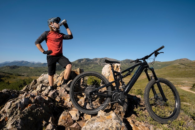 Adulto joven con bicicleta eléctrica en el campo