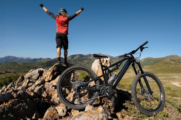 Adulto joven con bicicleta eléctrica en el campo