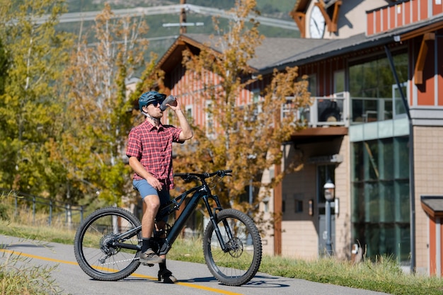 Adulto joven con bicicleta eléctrica en el campo