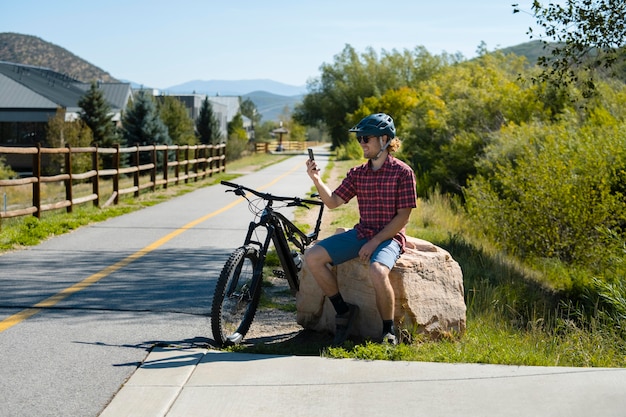 Adulto joven con bicicleta eléctrica en el campo