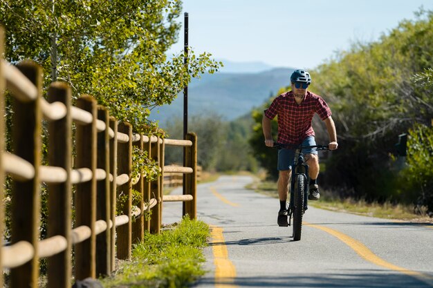 Adulto joven con bicicleta eléctrica en el campo