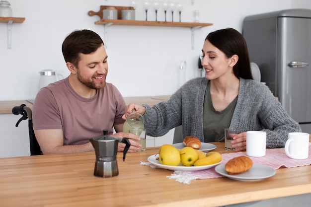 Adulto joven comiendo con un amigo discapacitado