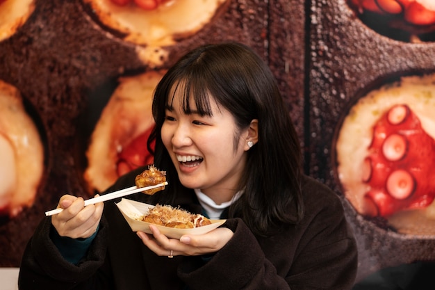 Adulto joven disfrutando de comida callejera japonesa