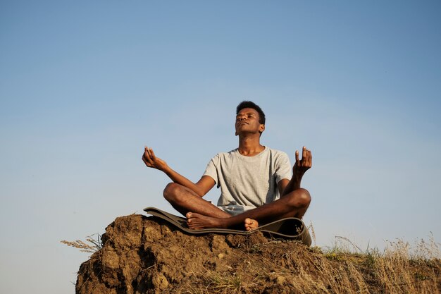 Adulto joven disfrutando del yoga en la naturaleza