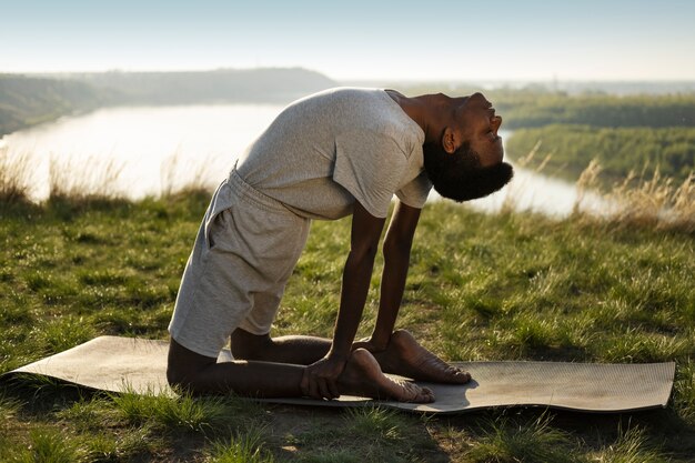 Adulto joven disfrutando del yoga en la naturaleza