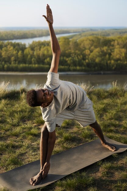 Adulto joven disfrutando del yoga en la naturaleza