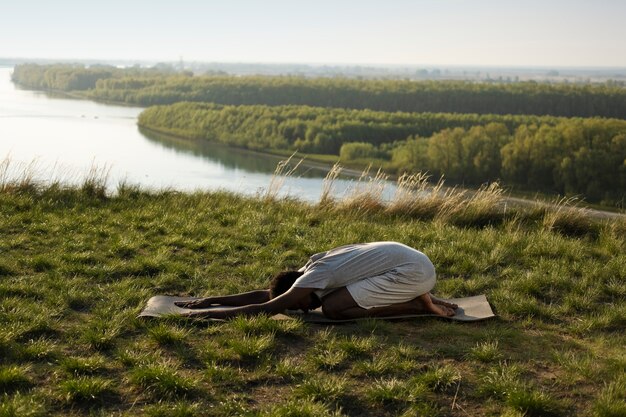 Adulto joven disfrutando del yoga en la naturaleza