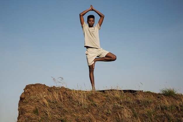 Adulto joven disfrutando del yoga en la naturaleza