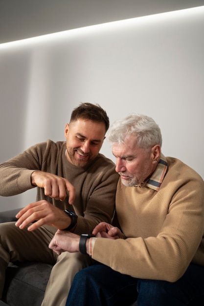 Adulto joven enseñando a anciano sobre devicer degital
