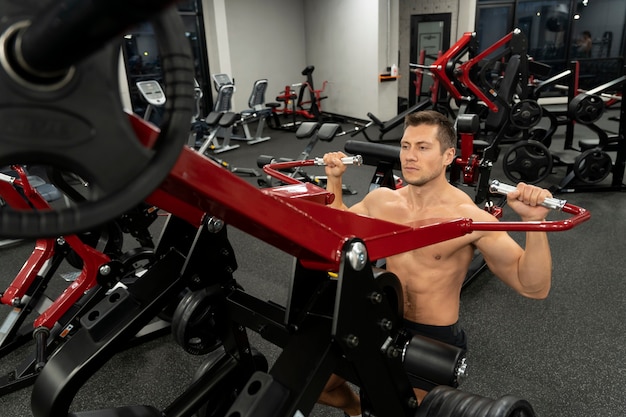 Foto gratuita adulto joven haciendo deporte de interior en el gimnasio