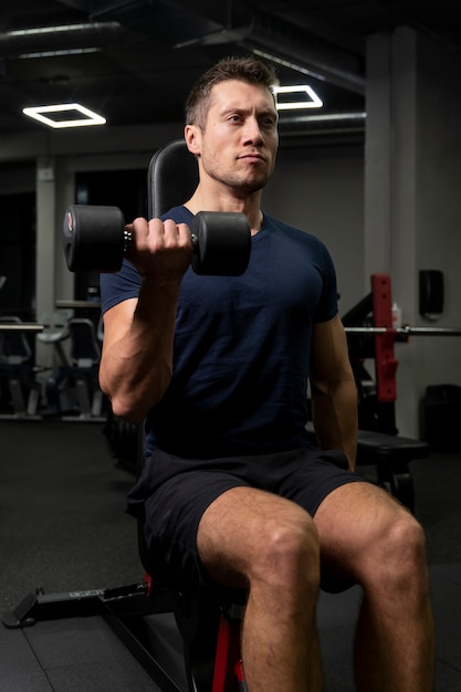 Foto gratuita adulto joven haciendo deporte de interior en el gimnasio