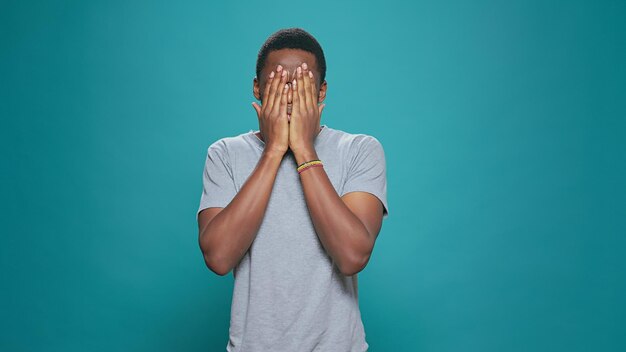 Adulto joven haciendo tres gestos de monos sabios en cámara, cubriendo ojos, boca y oídos como dichos de sabiduría. Persona moderna anunciando el concepto de silencio con la mano, reacción formal informal sobre el fondo.