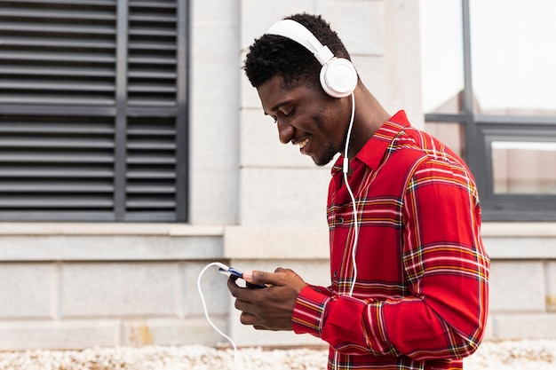 Adulto joven de lado en camisa roja escuchando música