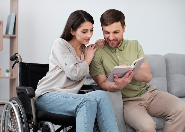 Foto gratuita adulto joven leyendo con un amigo discapacitado