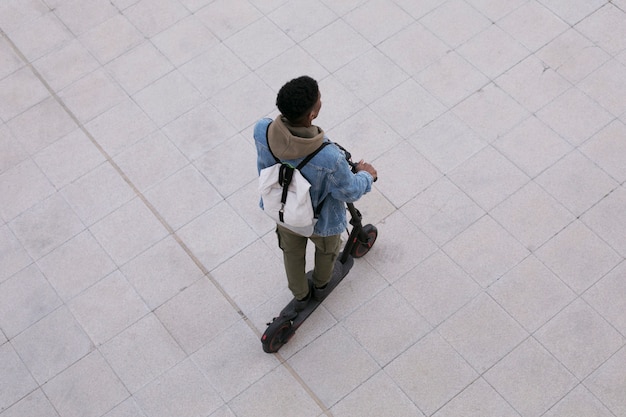 Adulto joven que usa scooter eléctrico para el transporte