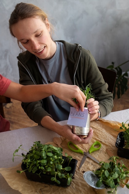 Foto gratuita adulto joven reutilizando latas para plantar