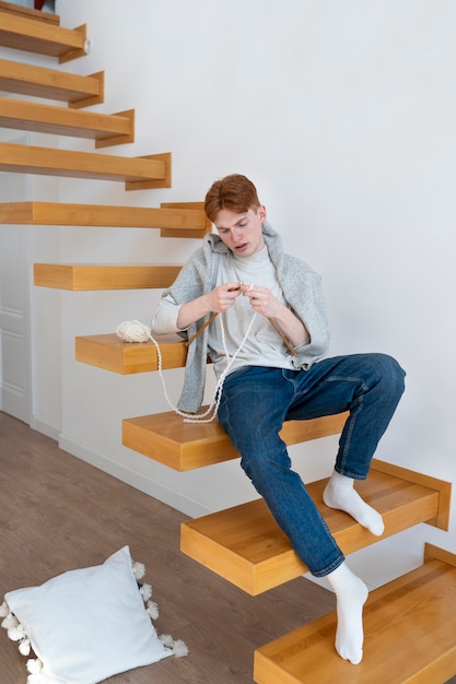 Foto gratuita adulto joven tejiendo en casa