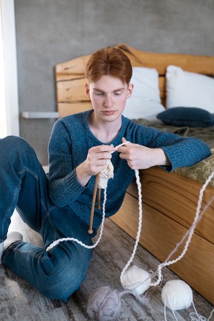 Foto gratuita adulto joven tejiendo en casa