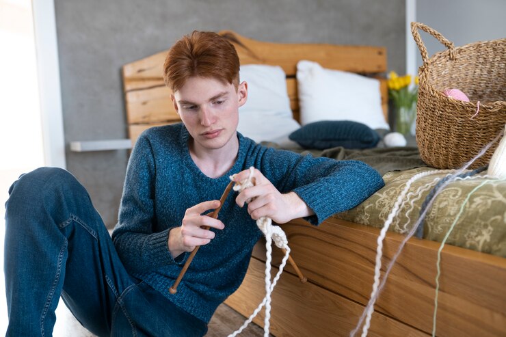 Foto gratuito adulto joven tejiendo en casa