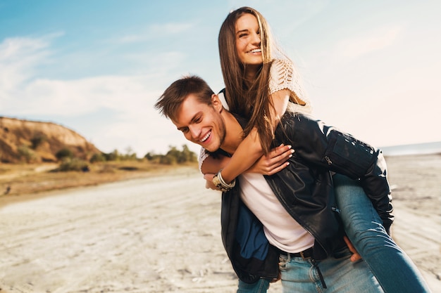 Adultos jóvenes novia y novio abrazando feliz. Joven bonita pareja de enamorados que datan en la primavera soleada a lo largo de la playa. Colores cálidos.