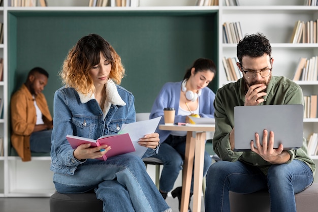 Foto gratuita adultos jóvenes que estudian desde una computadora portátil y una computadora portátil durante la sesión de estudio