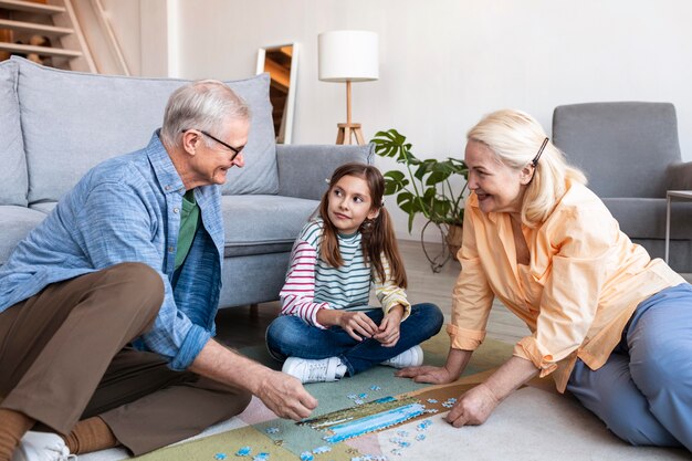 Adultos y niña haciendo rompecabezas en el piso