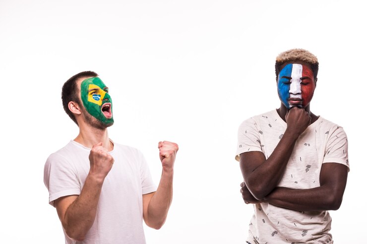 Foto gratuito aficionado al fútbol feliz de brasil celebrar victoria sobre aficionado al fútbol molesto de equipos nacionales de francia con la cara pintada aislado sobre fondo blanco.