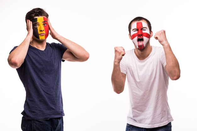 Aficionado al fútbol feliz de Inglaterra celebrar victoria sobre aficionado al fútbol molesto de Bélgica con la cara pintada aislado sobre fondo blanco.