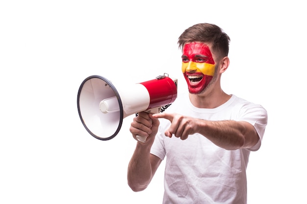 Aficionado al fútbol joven español con megáfono aislado en la pared blanca