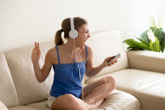 Aficionado a la música joven usando auriculares cantando