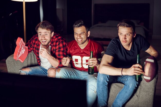 Aficionados al fútbol emocionados viendo fútbol americano por la noche