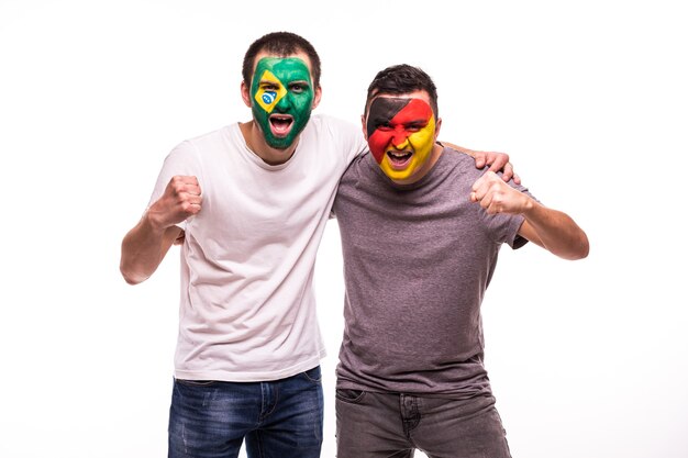 Los aficionados al fútbol partidarios con la cara pintada de los equipos nacionales de Brasil y Alemania aislado sobre fondo blanco.