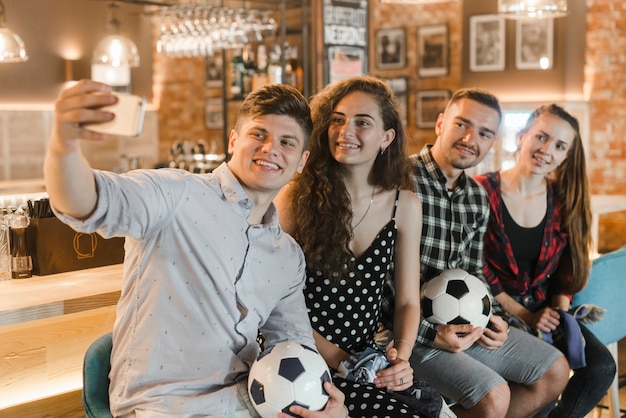 Foto gratuita aficionados al fútbol sentados en fila tomando selfie en el bar