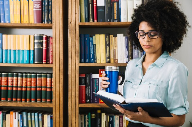 Afroamericana joven con termo y libro.