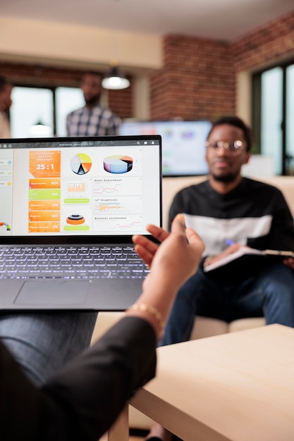 Afroamericanos analizando gráficos y diagramas de negocios en una computadora portátil para crear una presentación de inicio y un informe de papeleo. Colaboración en el trabajo en equipo para planificar la información de la investigación.