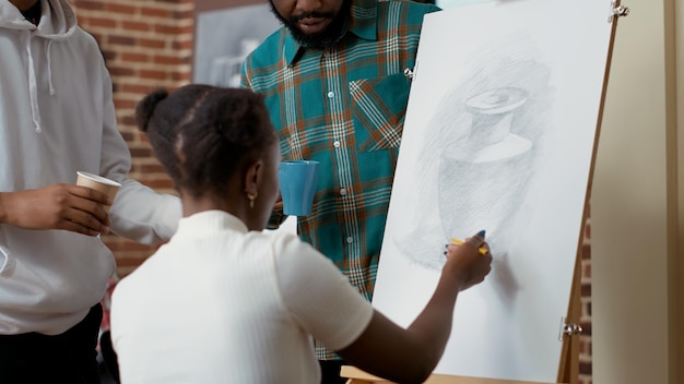 Los afroamericanos se inspiran en un jarrón juntos en la clase de arte, usan herramientas artísticas y lienzos para crear diseños de bocetos. Actividad creativa para desarrollar nuevas habilidades, para dibujar obras de arte modernas.