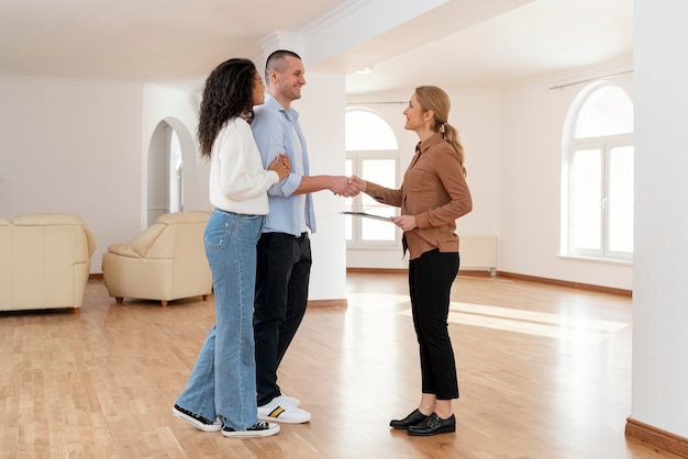 Agente de bienes raíces femenino un apretón de manos con la pareja para un nuevo trato de casa