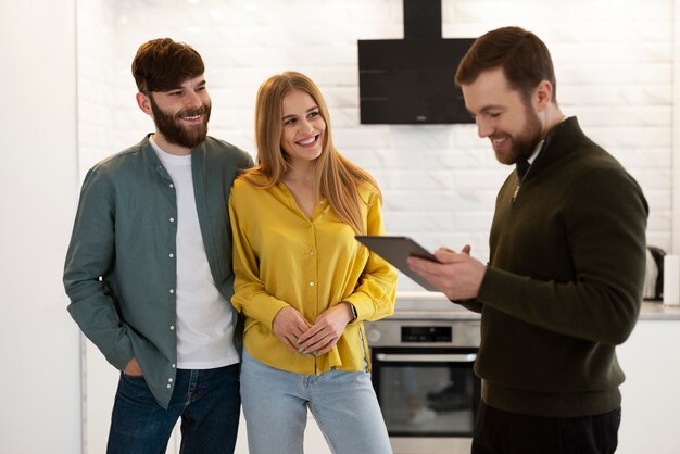 Agente inmobiliario masculino haciendo negocios y mostrando la casa a una posible pareja compradora