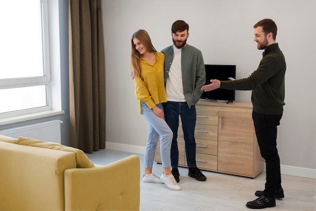 Agente inmobiliario masculino haciendo negocios y mostrando la casa a una posible pareja compradora