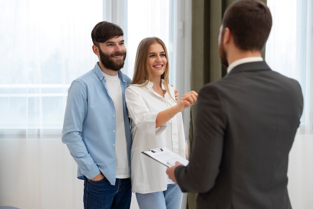 Foto gratuita agente inmobiliario masculino haciendo negocios y mostrando la casa a una posible pareja compradora