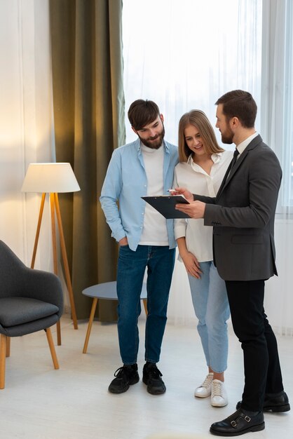 Agente inmobiliario masculino haciendo negocios y mostrando la casa a una posible pareja compradora