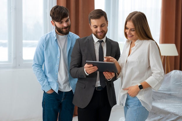 Foto gratuita agente inmobiliario masculino haciendo negocios y mostrando la casa a una posible pareja compradora