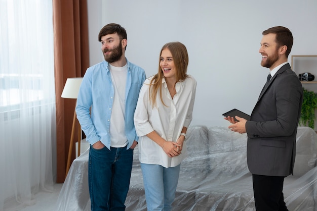 Agente inmobiliario masculino haciendo negocios y mostrando la casa a una posible pareja compradora