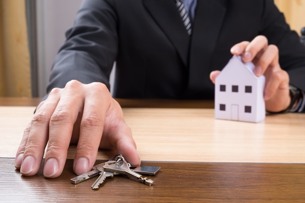 Agente inmobiliario con modelo de casa y llaves