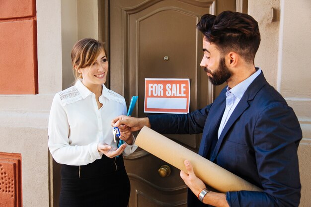 Agente inmobiliario y mujer de negocios en frente de una puerta