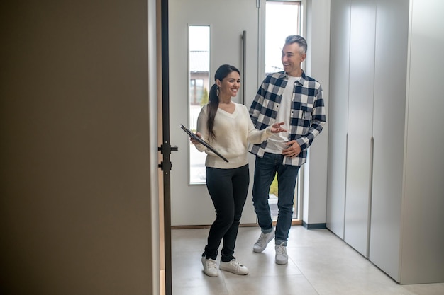 Agente inmobiliario Mujer sonriente que muestra a un hombre de mediana edad interesado y alegre su nuevo hogar durante el día